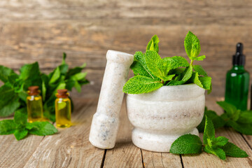 Fresh mint with mortar and pestle on wooden background. Melissa leaves. Healing herbs green mint...