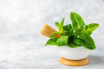 Fresh mint with mortar and pestle on wooden background. Melissa leaves. Healing herbs green mint...