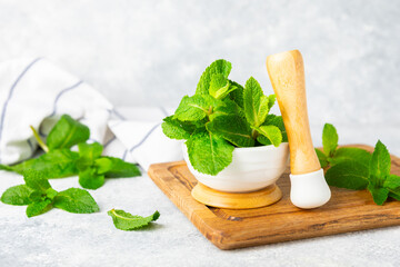 Fresh mint with mortar and pestle on wooden background. Melissa leaves. Healing herbs green mint leaves in mortar for medicine.Space for text. Copy space.