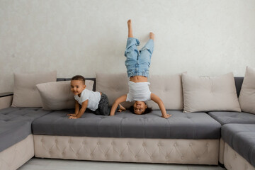 two young African-American children jumping on the couch at home
