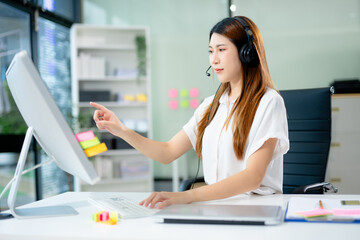 Young woman in headset taking notes during customer support session. Great for themes like online...