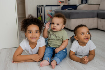Obraz premium three African-American children lie on the wooden floor of a house