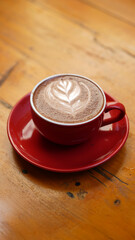 Creamy Latte Art in Vibrant Red Cup on Minimalist Wooden Table – Portrait Orientation