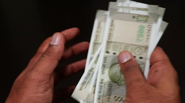 person's hands counting crisp banknotes of Indian 500 rupee currency notes in black background. stable shot, 4k.