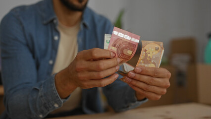 Man counting euro bills in a cozy living room interior, highlighting financial planning in a new...