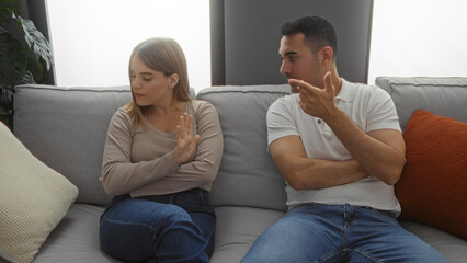 Man and woman sitting in living room on couch discussing relationship issues indoors in cozy...