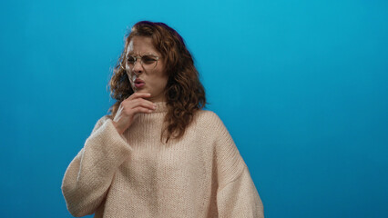 Woman making disgusted facial expression against isolated blue background wearing cozy sweater...