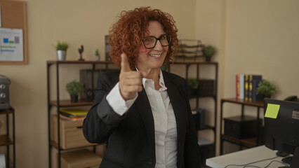 Woman smiling in office giving thumbs up and clapping in a business environment, showcasing...
