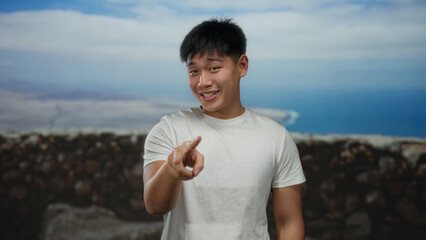 Young chinese man making a playful gesture on a seaside promenade with scenic ocean views in the...