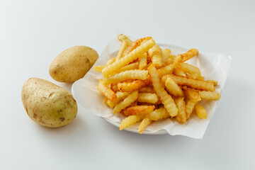 Fresh Crispy Crinkle Cut French Fries and Raw Potatoes on White Background