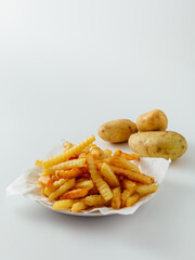 Freshly Cooked Crinkle Cut Fries with Raw Potatoes on White Background