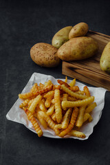 Crispy Crinkle-Cut Fries with Fresh Potatoes on Dark Background