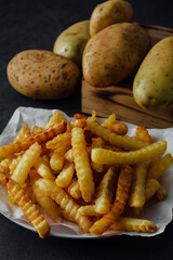 Crispy Crinkle Cut Fries Served with Fresh Potatoes on a Dark Background