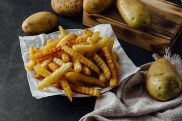 Crispy Golden Fried Crinkle Cut Potatoes on Plate with Raw Potatoes