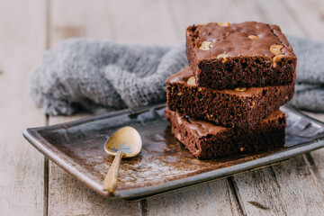 Delicious Brownies with Nuts on Metallic Plate and Wooden Background