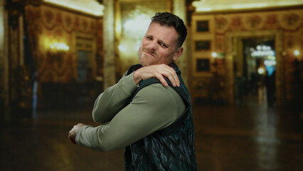 Man with beard and blue vest standing indoors in a historic museum setting, showing an uncertain...
