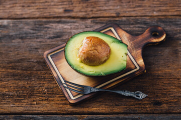 Fresh Avocado Halved on Wooden Cutting Board with Fork