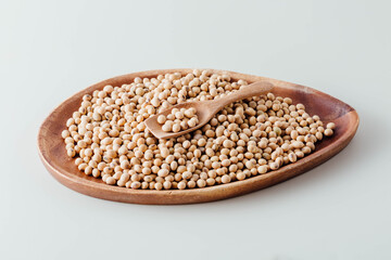Wooden Bowl with Raw Soybeans and Wooden Spoon on White Surface