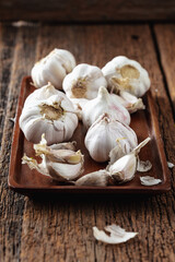 Fresh Garlic Cloves on Rustic Wooden Plate with Natural Background