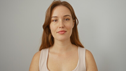 Woman with red hair poses against a white background showcasing natural beauty in an isolated studio setting that emphasizes her attractive features and serene expression.