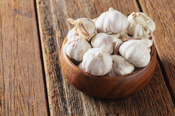 Fresh Garlic Bulbs in Wooden Bowl on Rustic Wooden Table Surface