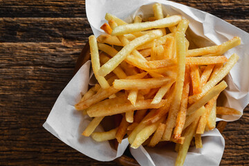 Freshly Cooked Crispy French Fries in a Paper Basket on Wood