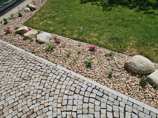 flowerbed with perennials and stones made of gray granite, mulched pebbles in the city garden,...