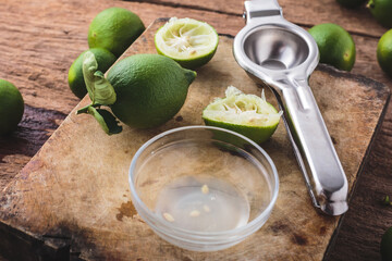 Fresh Limes with Juicer and Sliced Fruit on Wooden Cutting Board