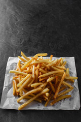 Golden Crispy French Fries Served on White Paper with Dark Background