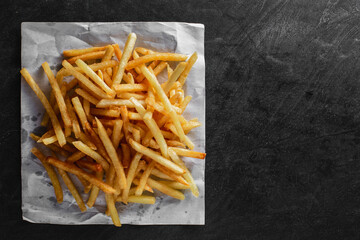 Crispy Golden French Fries on a Dark Surface with Paper Lining