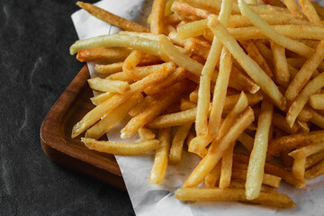 Crispy Golden French Fries on Wooden Platter with Dark Background