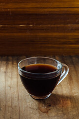 Warm Coffee in Glass Cup on Rustic Wooden Table Background