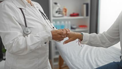 Doctor holding patient's hand in a clinic room, demonstrating compassionate healthcare interaction...