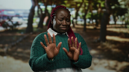 Woman expressing rejection in a park with trees around her showing outdoor scene with vivid...