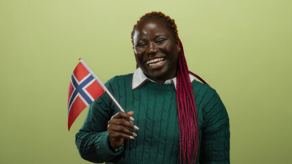 Woman holding norwegian flag against yellow background in isolated joyful setting, showcasing...