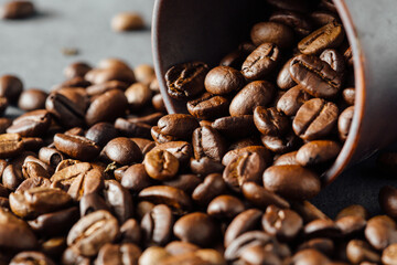Fototapeta premium Freshly Roasted Coffee Beans Spilling from a Cup on Dark Surface