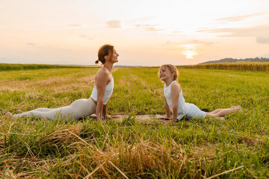 Mother and daughter practicing yoga poses in nature.
