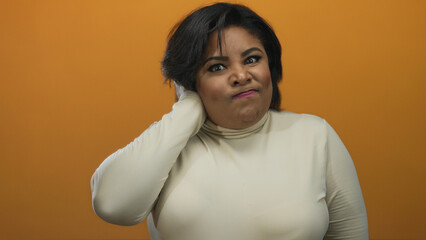 Woman on orange background gestures unsure, with eyes closed and hand on neck, expressing confusion...