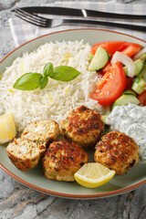 Greek chicken meatballs with feta cheese served with lemon rice and vegetable salad close-up in a...