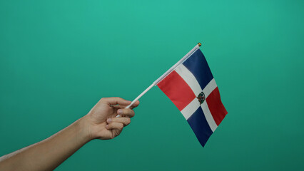 Caucasian man holding dominican republic flag on green isolated background with visible hand in...