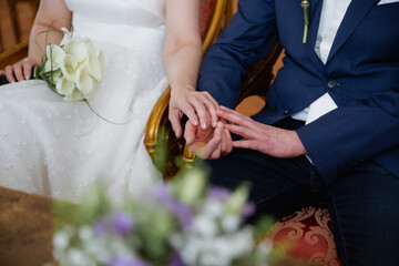 Close up of bride and groom holding hands sitting together, wedding day concept