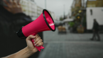 Man holding pink megaphone in city street signifies public announcement, showcasing hand raised...