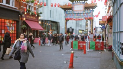 Woman walking through blurred chinatown london street scene with winter attire and bokeh lights...