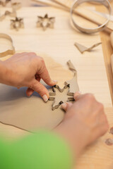 Ceramist using snowflake cookie cutter creating christmas clay decorations