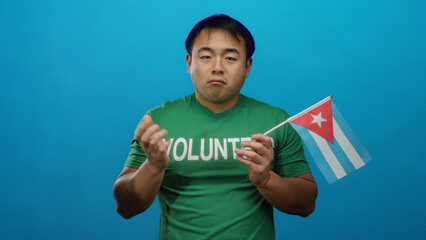 Young man in green shirt holds cuba flag against blue background, showcasing volunteer support with...