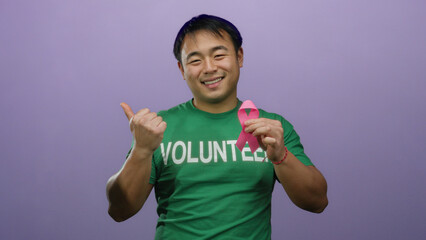 Asian man volunteer holding pink ribbon against purple background promoting breast cancer awareness...