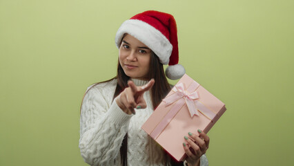 Woman in santa hat holding gift making peace sign on yellow background expressing festive joy and warmth