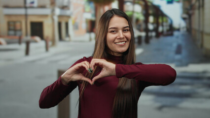 Woman making heart gesture on urban street showing happiness and positivity in vibrant setting with...