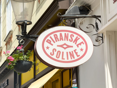 Ljubljana, Slovenia - June 03, 2025: Piranske Soline sign hanging outside a charming shop, adorned with vibrant flowers, showcasing local culture and inviting atmosphere in a picturesque street