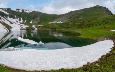 Glacial lake in low clouds in changeable weather